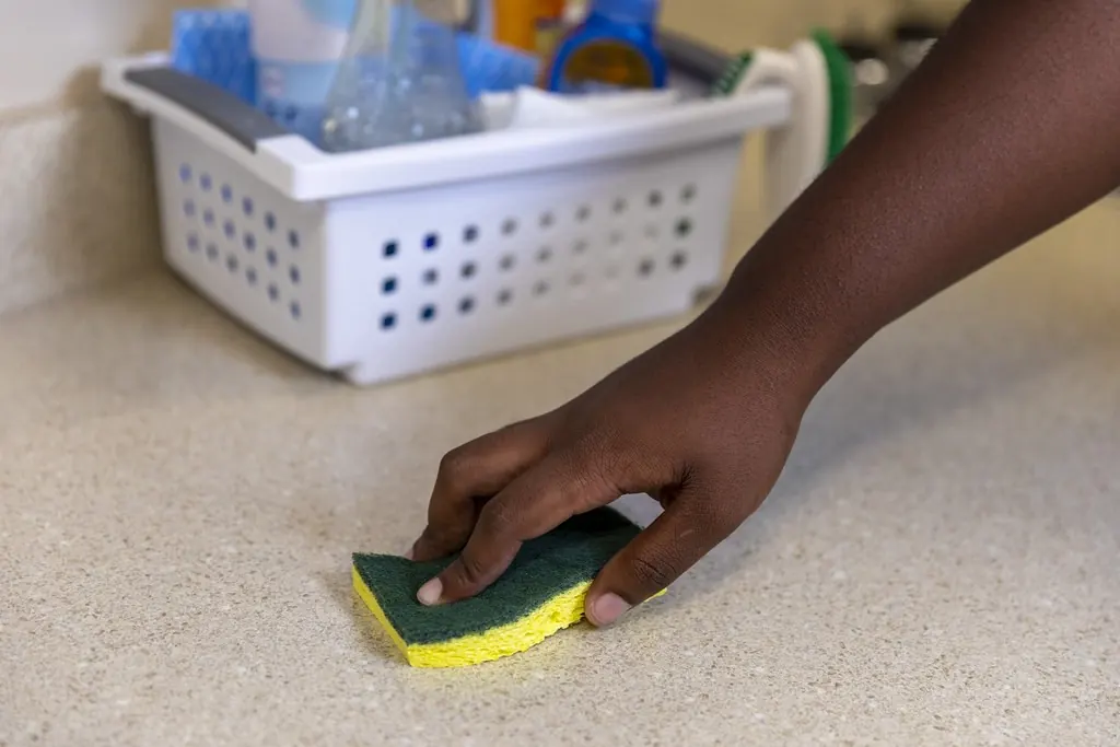 Hand scrubbing a countertop with a sponge