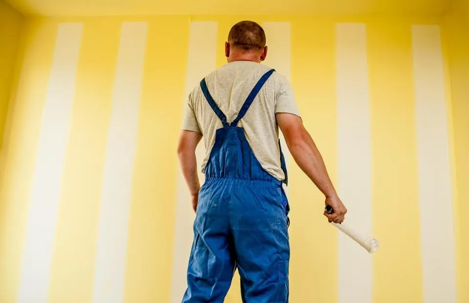 Painter in overalls preparing to paint a striped wall
