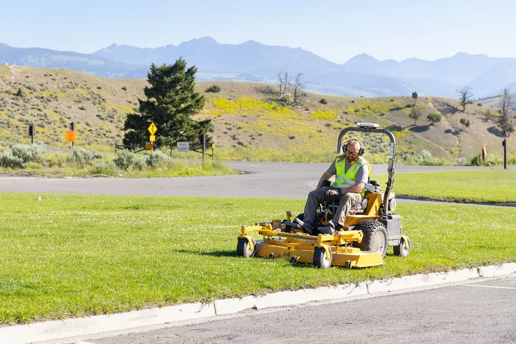 Worker mowing a wide lawn with a ride-on mower