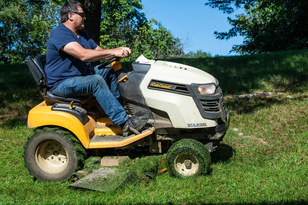 Man mowing tall grass with a yellow riding mower