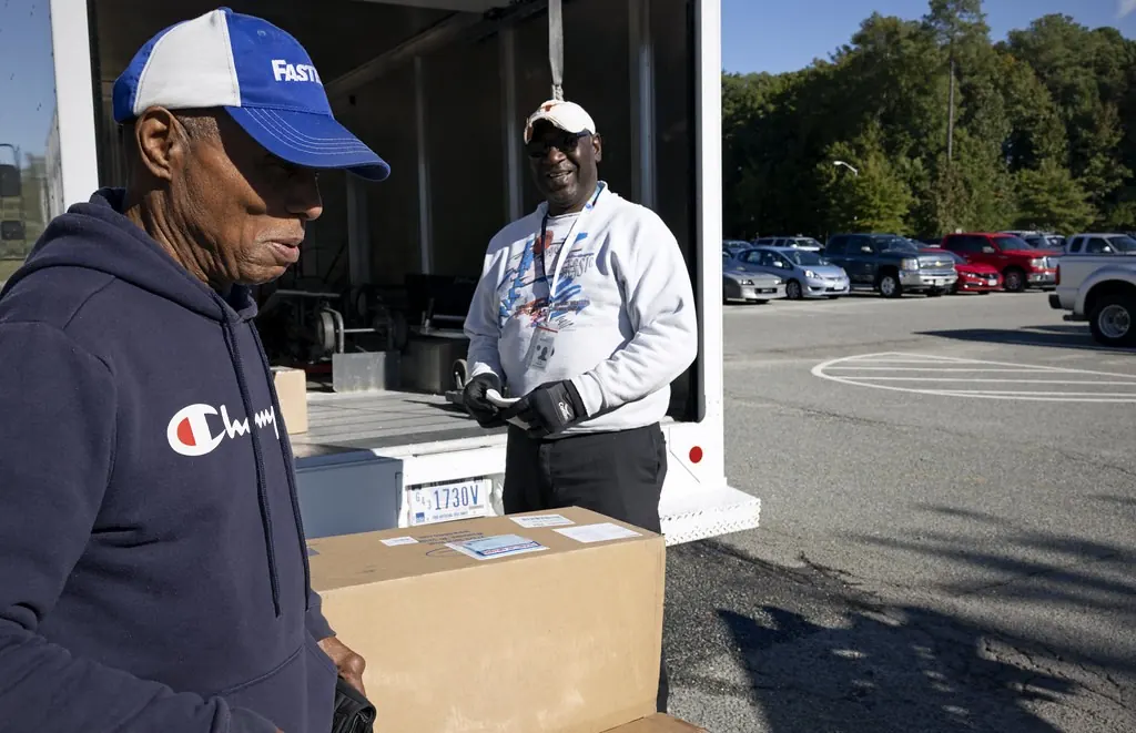 Delivery workers handing off a box beside a van